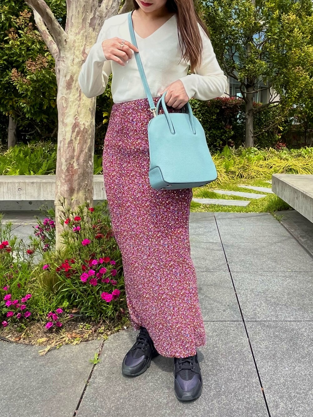 ブルー系のショルダーバッグ、レッド系のスカート、ホワイト系のスニーカーを着用したレディースの春コーディネートの3枚目の写真