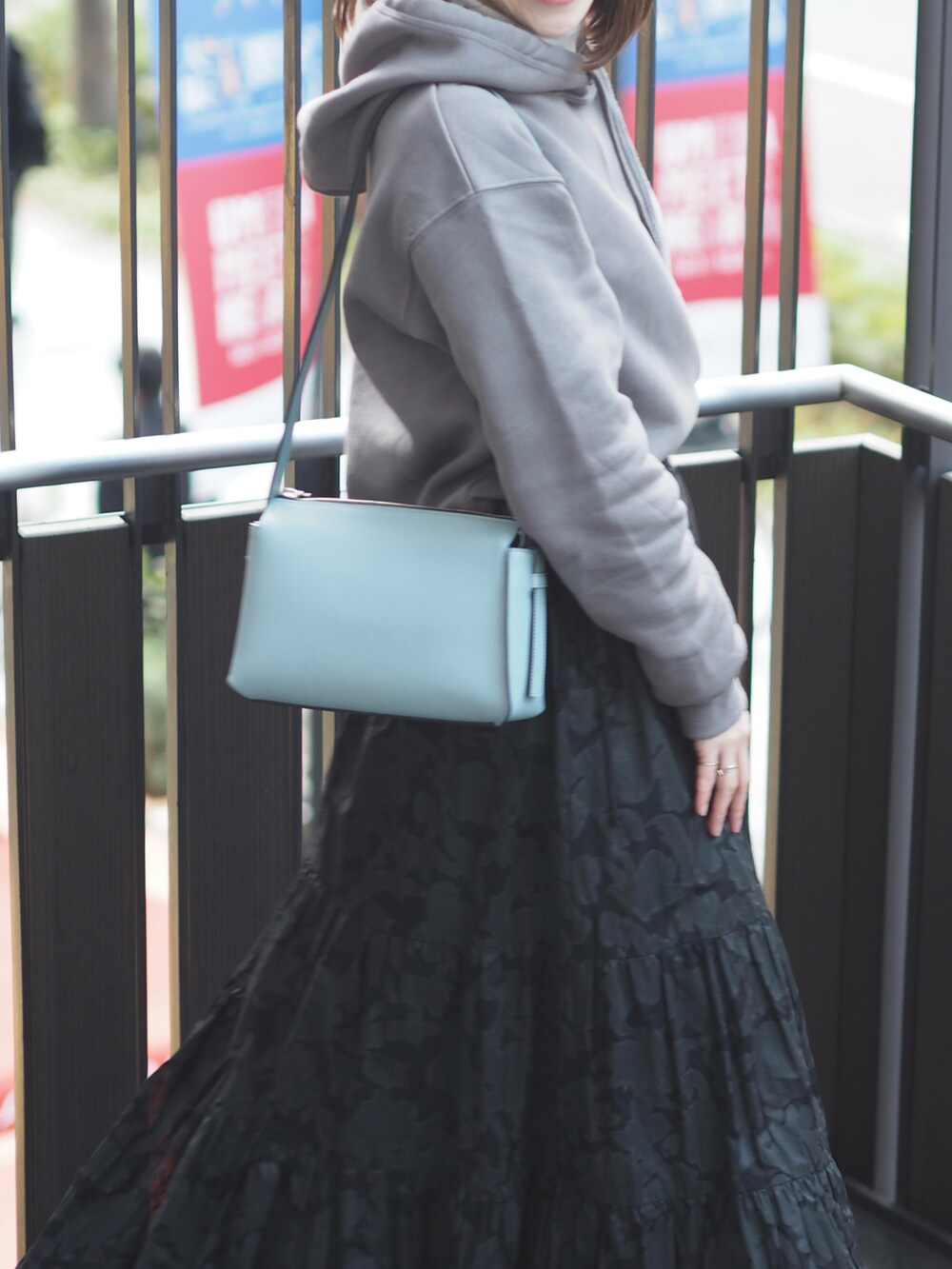 ブラック系のスカート、ブルー系のショルダーバッグ、グレー系のスウェットを着用したレディースの冬コーディネートの2枚目の写真