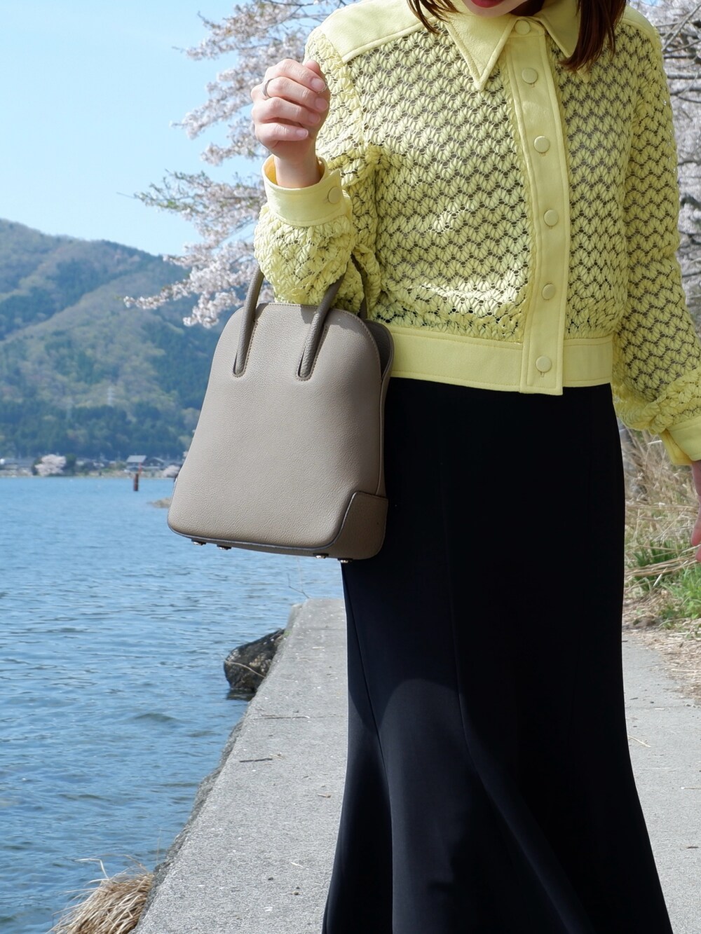 ブラウン系のショルダーバッグ、ブラック系のパンプス、イエロー系のシャツ/ブラウスを着用したレディースの春コーディネートの4枚目の写真