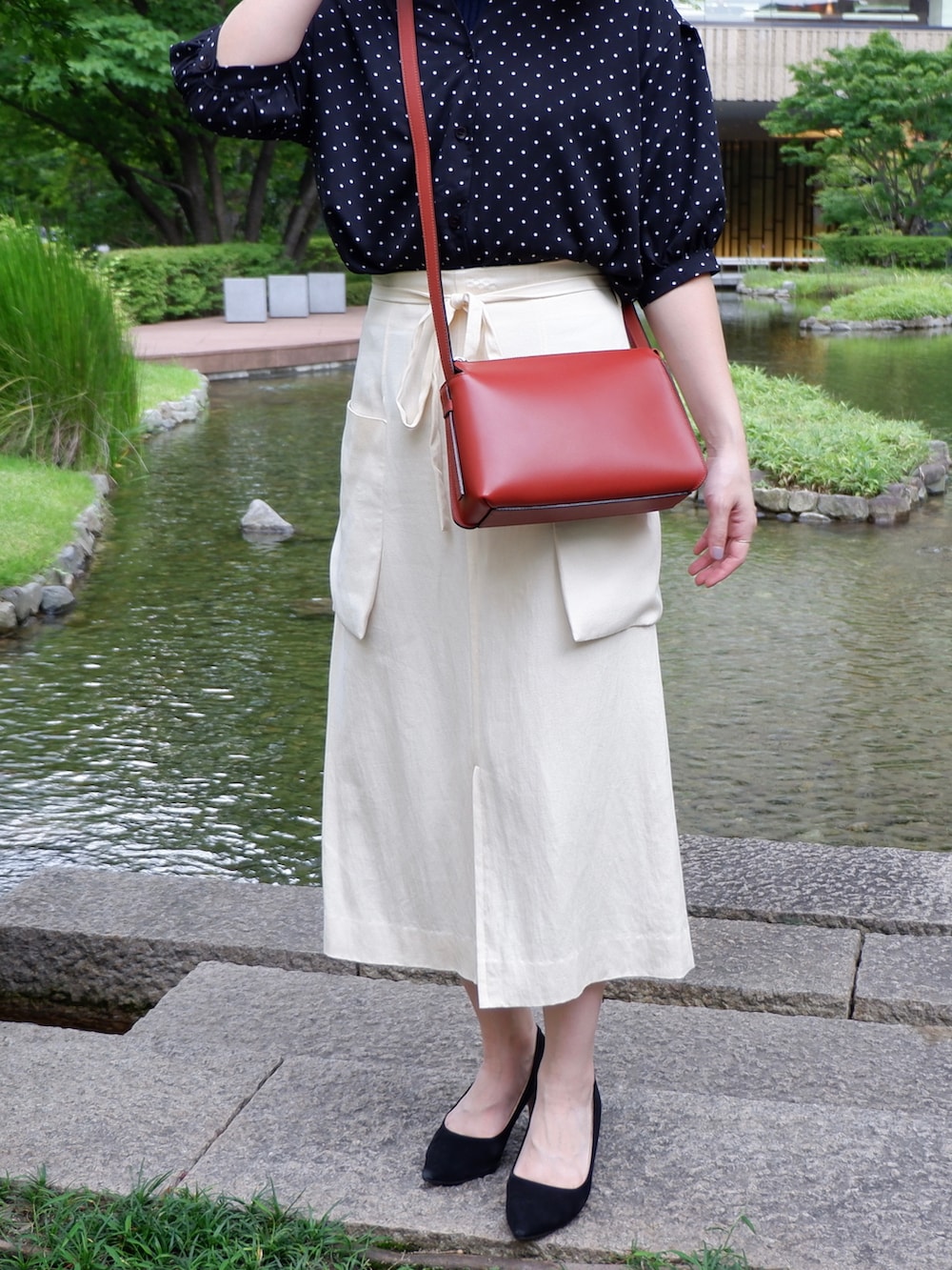 ブラック系のシャツ/ブラウス、ホワイト系のスカート、ブラック系のパンプスを着用したレディースの秋コーディネートの2枚目の写真