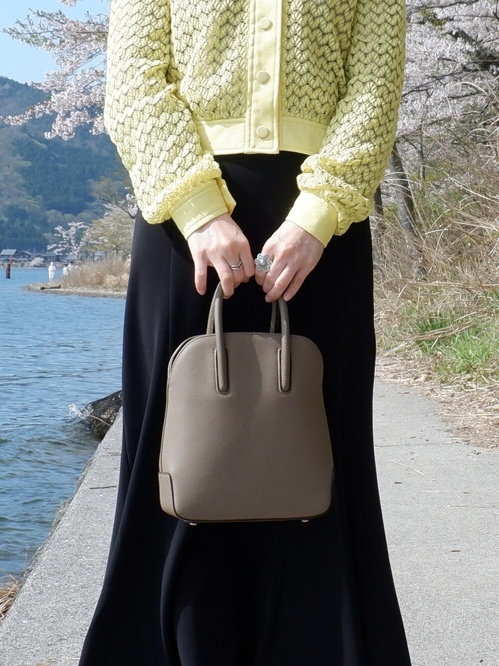 ブラウン系のショルダーバッグ、ブラック系のパンプス、イエロー系のシャツ/ブラウスを着用したレディースの春コーディネートの3枚目の写真