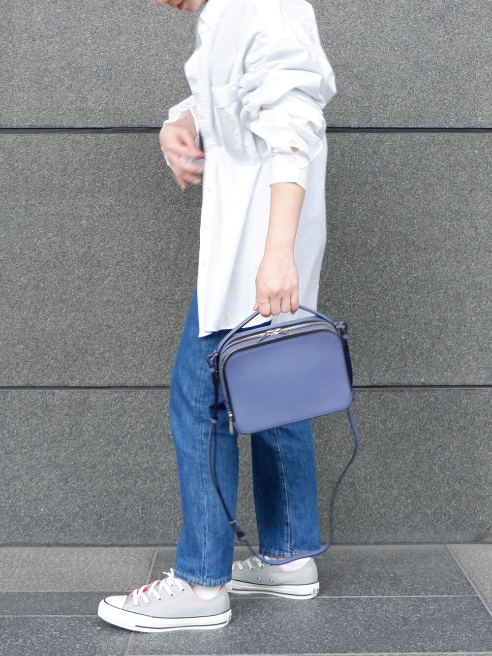 ブルー系のデニムパンツ、グレー系のスニーカー、パープル系のショルダーバッグを着用したレディースの夏コーディネートの3枚目の写真