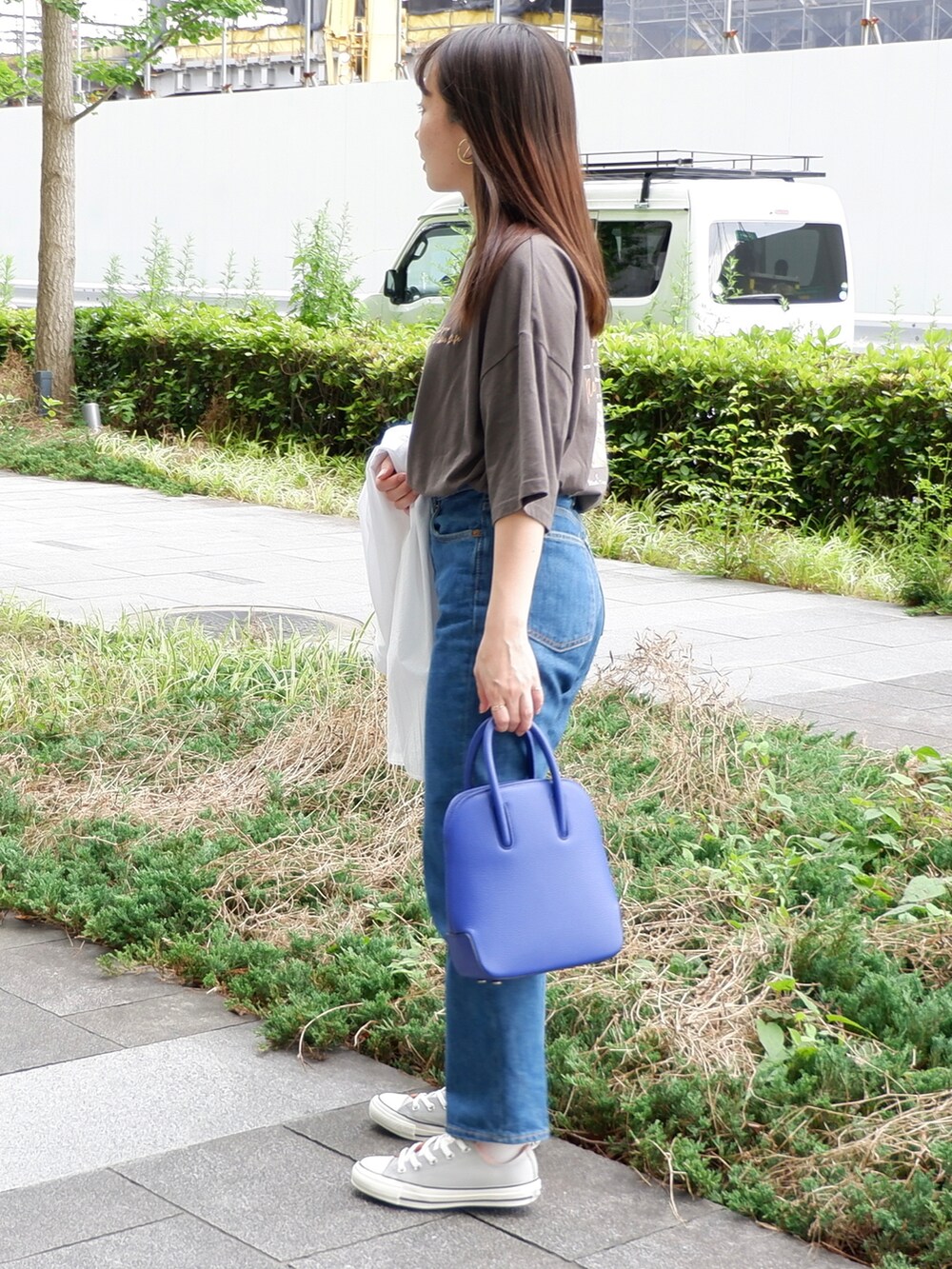 ブルー系のデニムパンツ、グレー系のスニーカー、ブルー系のショルダーバッグを着用したレディースの夏コーディネートの2枚目の写真