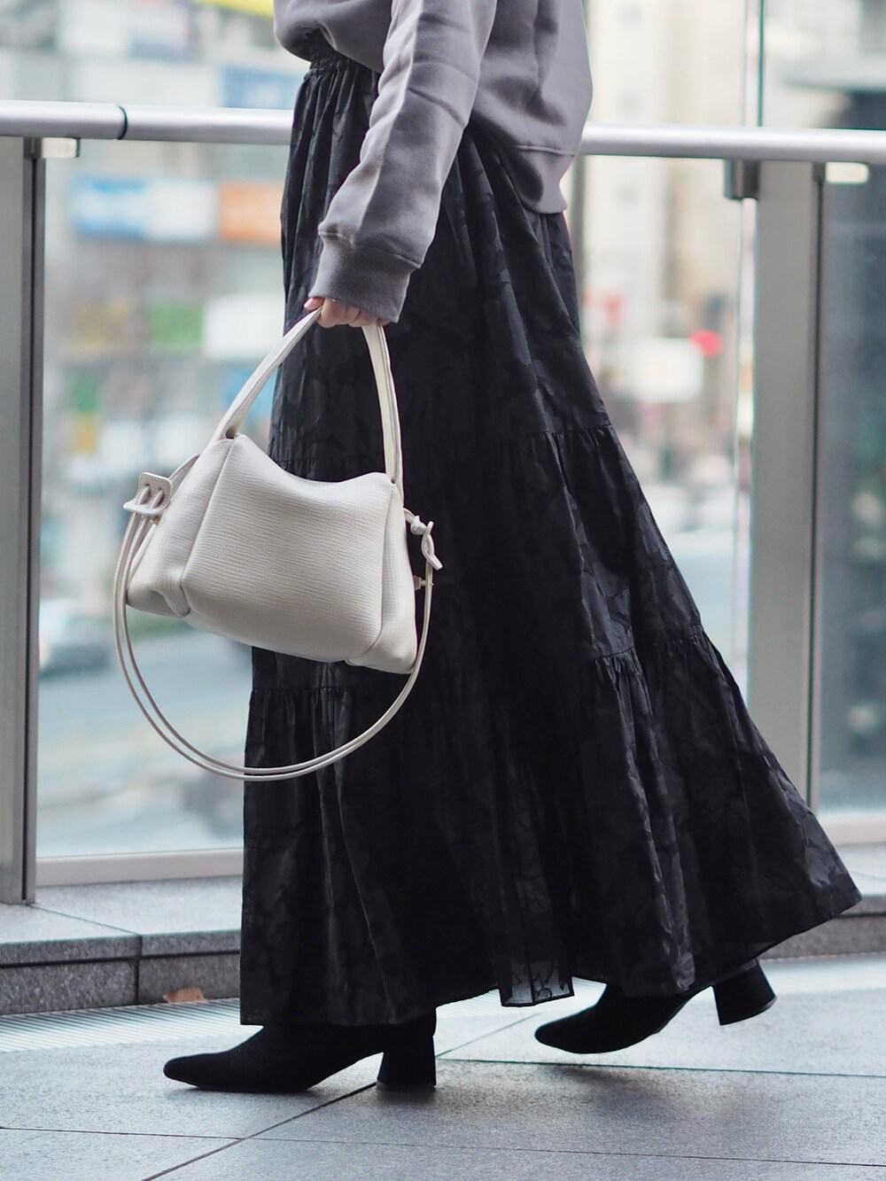 ホワイト系のショルダーバッグ、グレー系のスウェット、ブラック系のスカートを着用したレディースの冬コーディネートの4枚目の写真