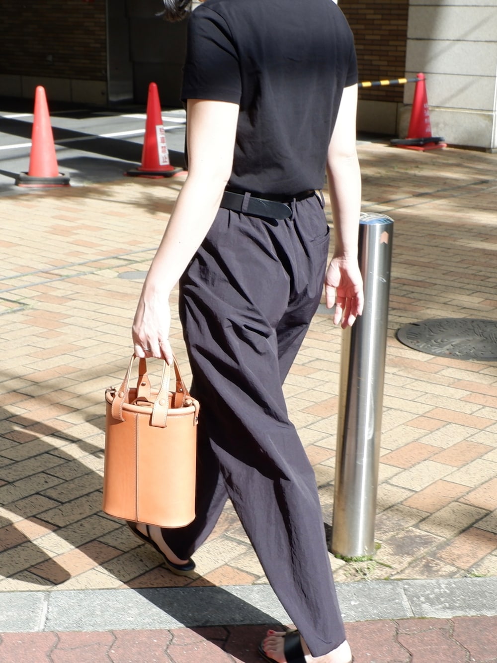 オレンジ系のバッグ、ブラック系のその他パンツ、ブラック系のサンダルを着用したレディースの夏コーディネートの2枚目の写真