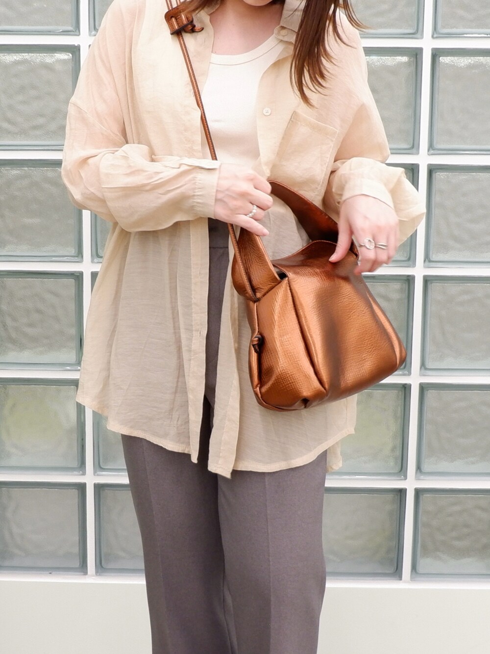グレー系のスラックス、ブラウン系のバッグ、ベージュ系のシャツ/ブラウスを着用したレディースの春コーディネートの3枚目の写真