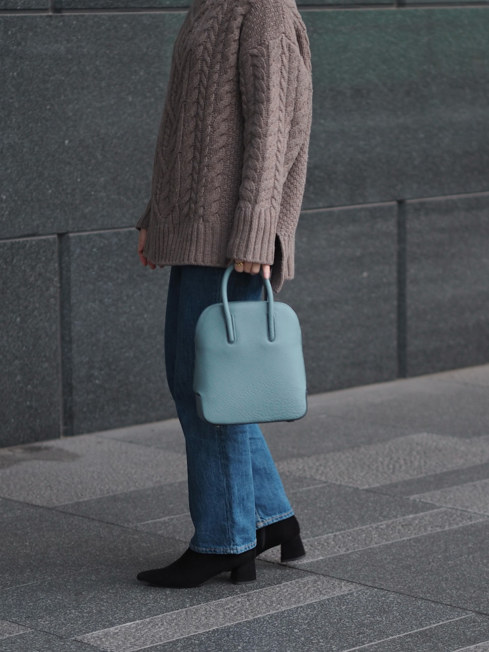 ブルー系のデニムパンツ、ブラック系のブーツ、ブラウン系のニット/セーターを着用したレディースの冬コーディネートの2枚目の写真