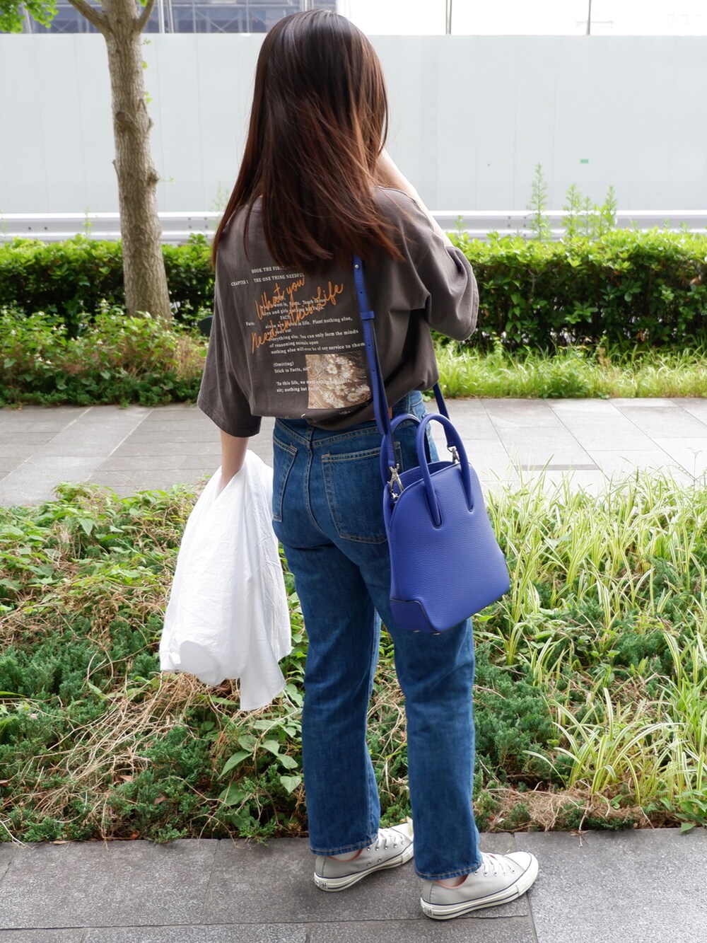 ブルー系のデニムパンツ、グレー系のスニーカー、ブルー系のショルダーバッグを着用したレディースの夏コーディネートの3枚目の写真