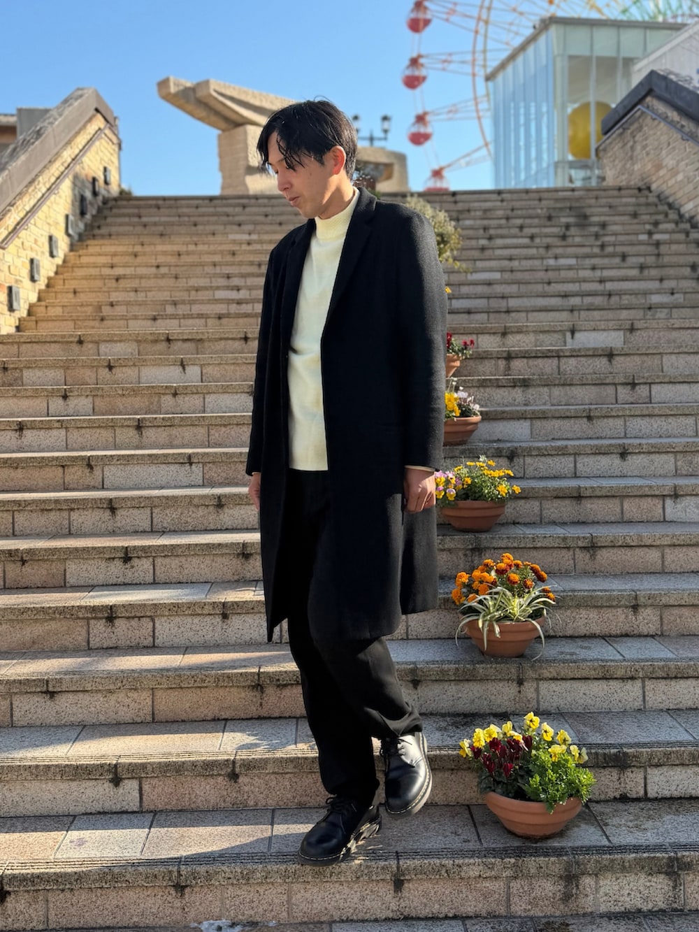 ブラック系のチェスターコート、ホワイト系のニット/セーター、ブラック系のドレスシューズを着用したメンズの冬コーディネートの3枚目の写真