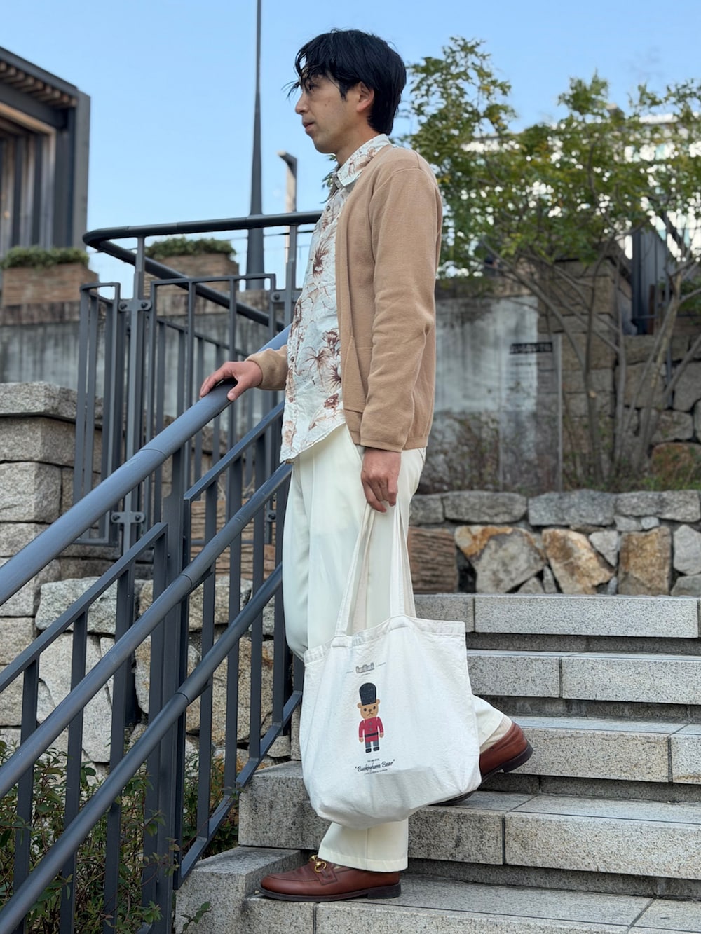 ホワイト系のスラックス、ベージュ系のトートバッグを着用したメンズの春コーディネートの3枚目の写真
