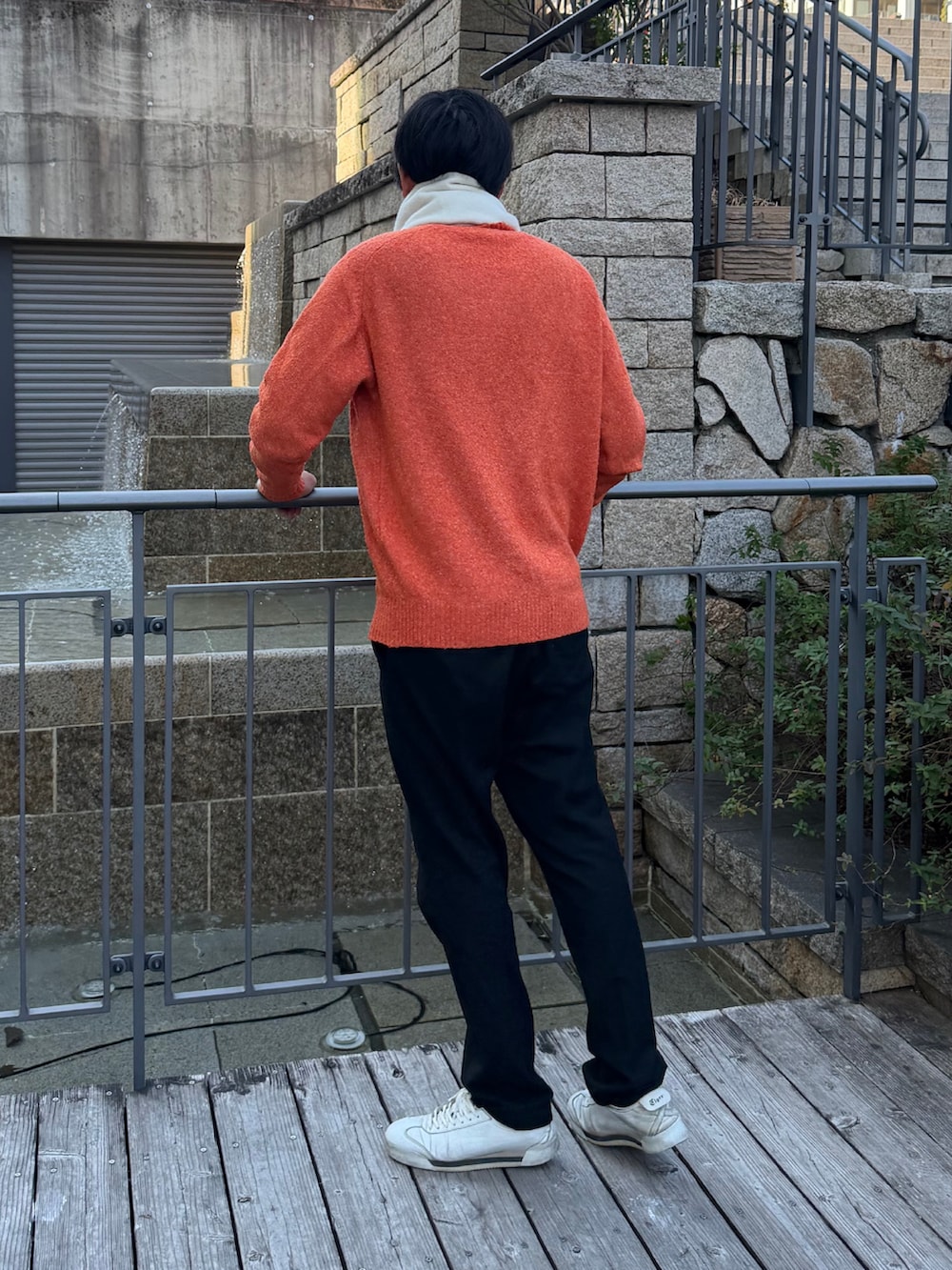 オレンジ系のニット/セーター、ホワイト系のスニーカー、ホワイト系のマフラーを着用したメンズの冬コーディネートの3枚目の写真