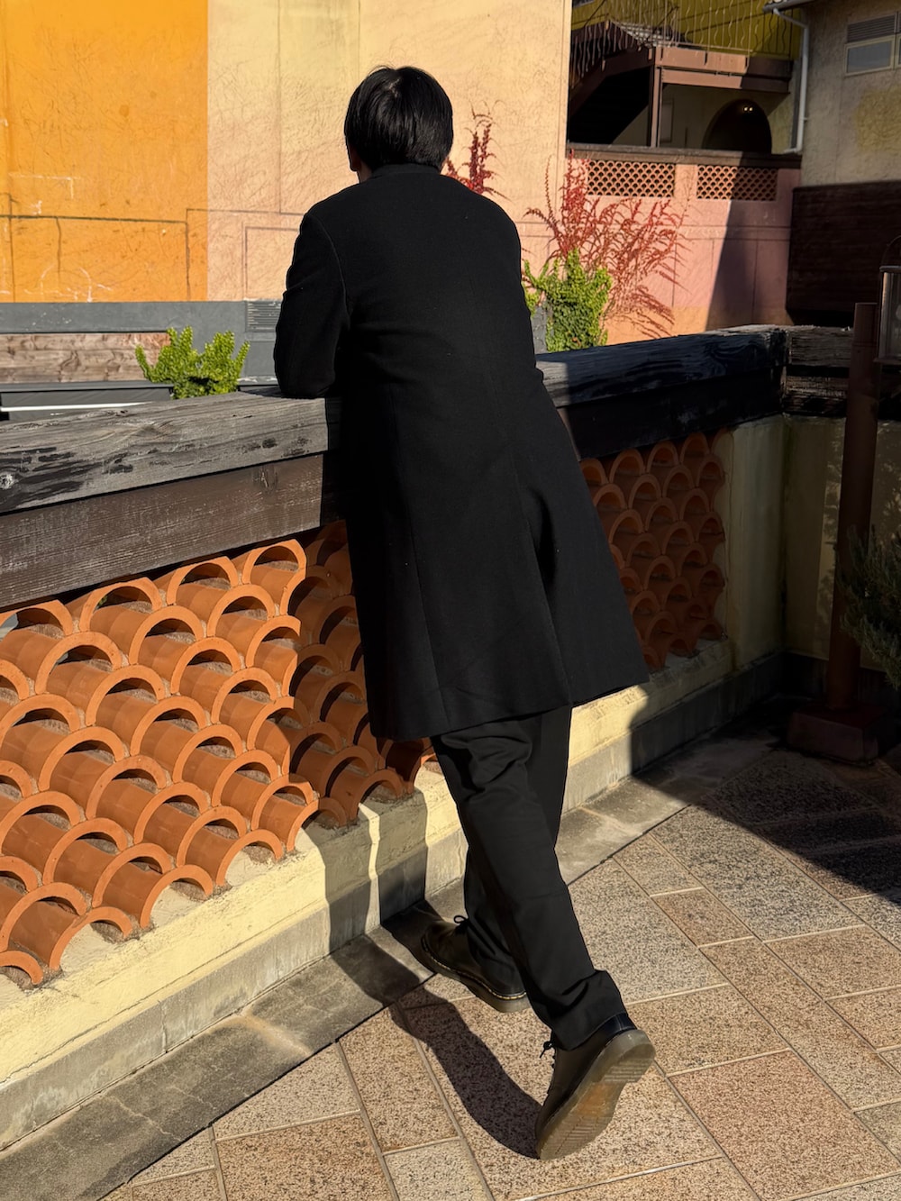 ブラック系のチェスターコート、ホワイト系のニット/セーター、ブラック系のドレスシューズを着用したメンズの冬コーディネートの2枚目の写真