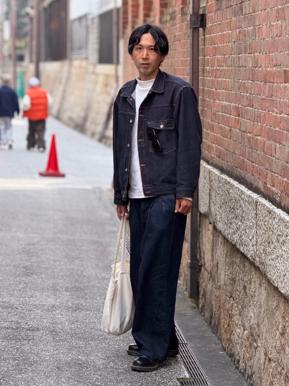 ブルー系のデニムジャケット、ブルー系のデニムパンツ、ベージュ系のトートバッグを着用したメンズの春コーディネートの4枚目の写真