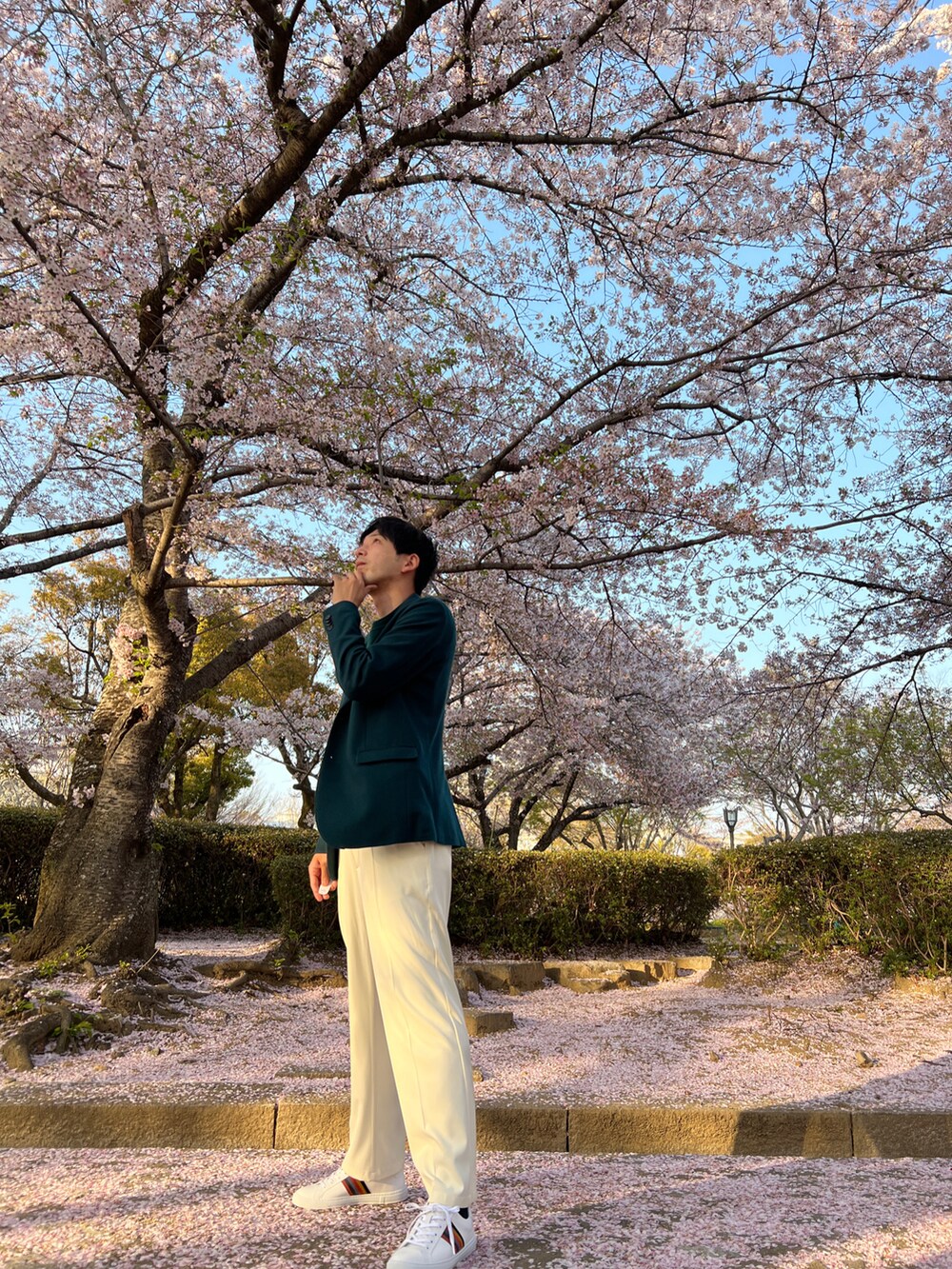 グリーン系のテーラードジャケット、ホワイト系のスラックス、ホワイト系のスニーカーを着用したメンズの春コーディネートの2枚目の写真