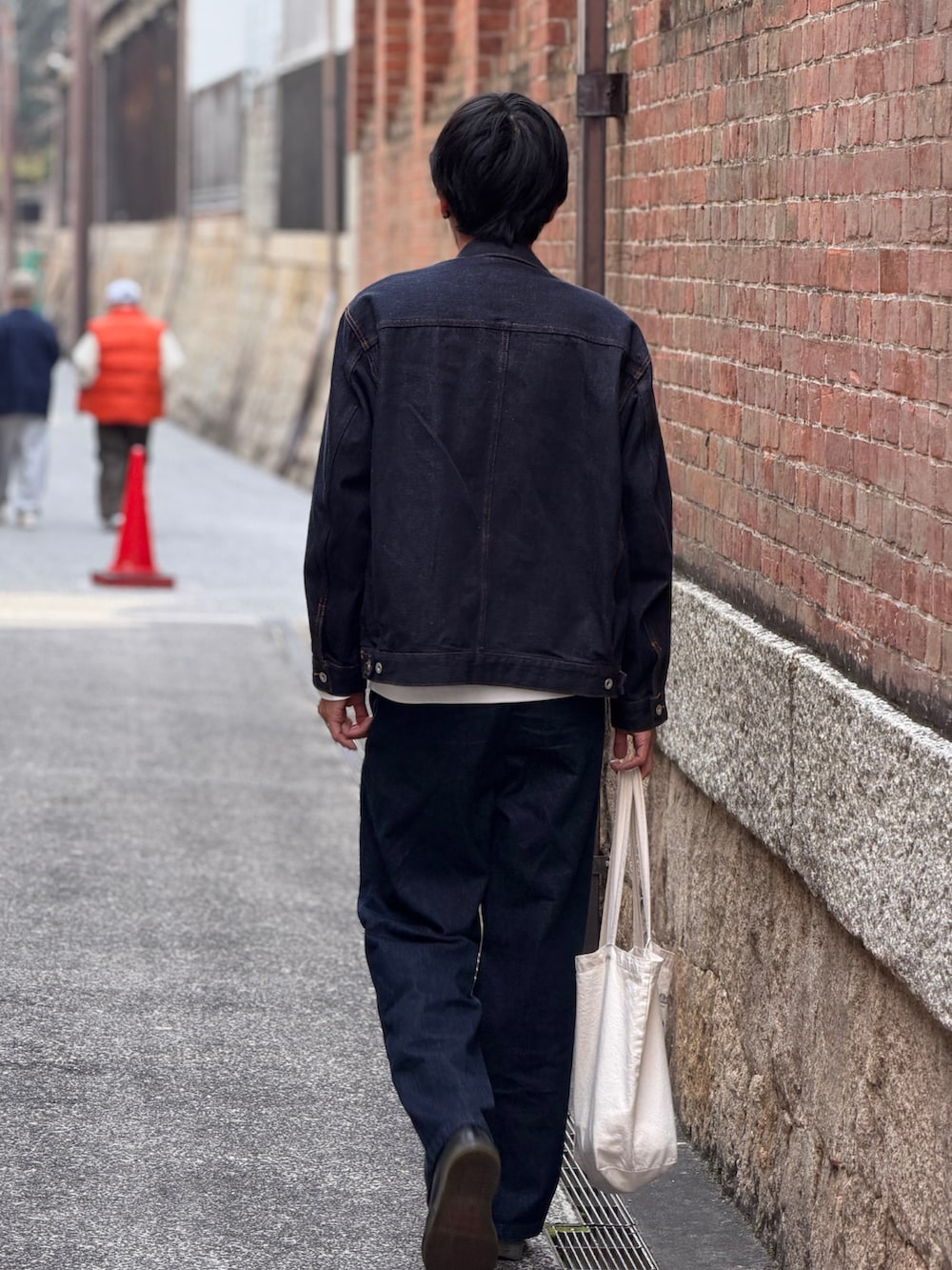 ブルー系のデニムジャケット、ブルー系のデニムパンツ、ベージュ系のトートバッグを着用したメンズの春コーディネートの3枚目の写真