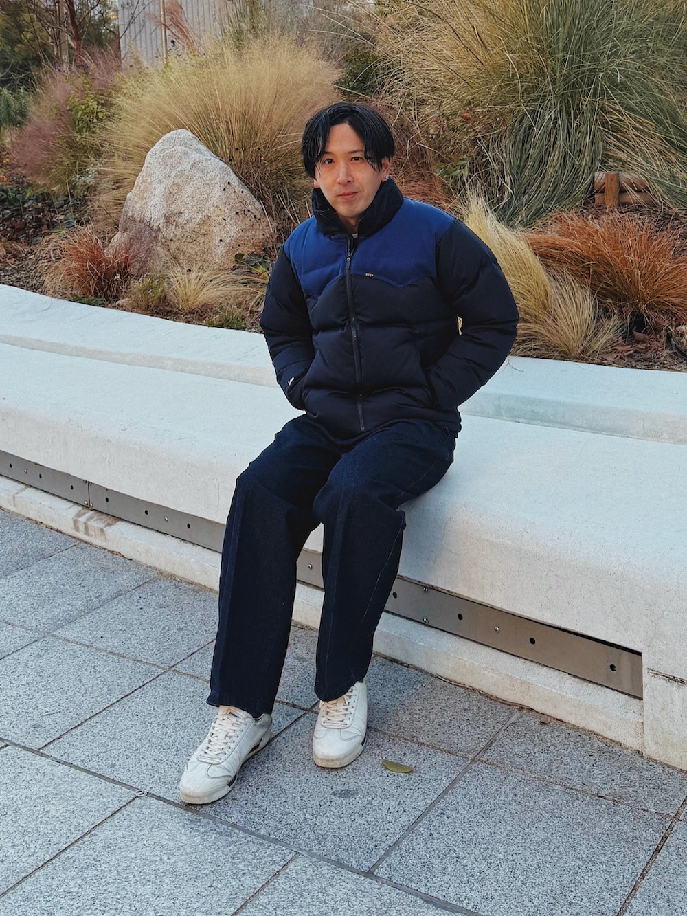 ブルー系のダウンジャケット/コート、ブルー系のデニムパンツ、ホワイト系のスニーカーを着用したメンズの冬コーディネートの2枚目の写真