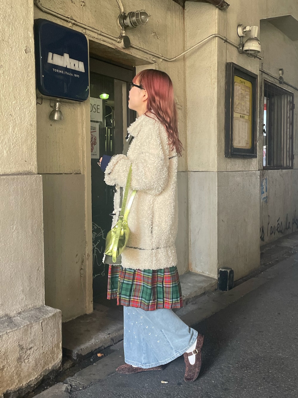 ホワイト系のダッフルコート、グリーン系のハンドバッグ、ブルー系のデニムパンツを着用したレディースの冬コーディネートの2枚目の写真