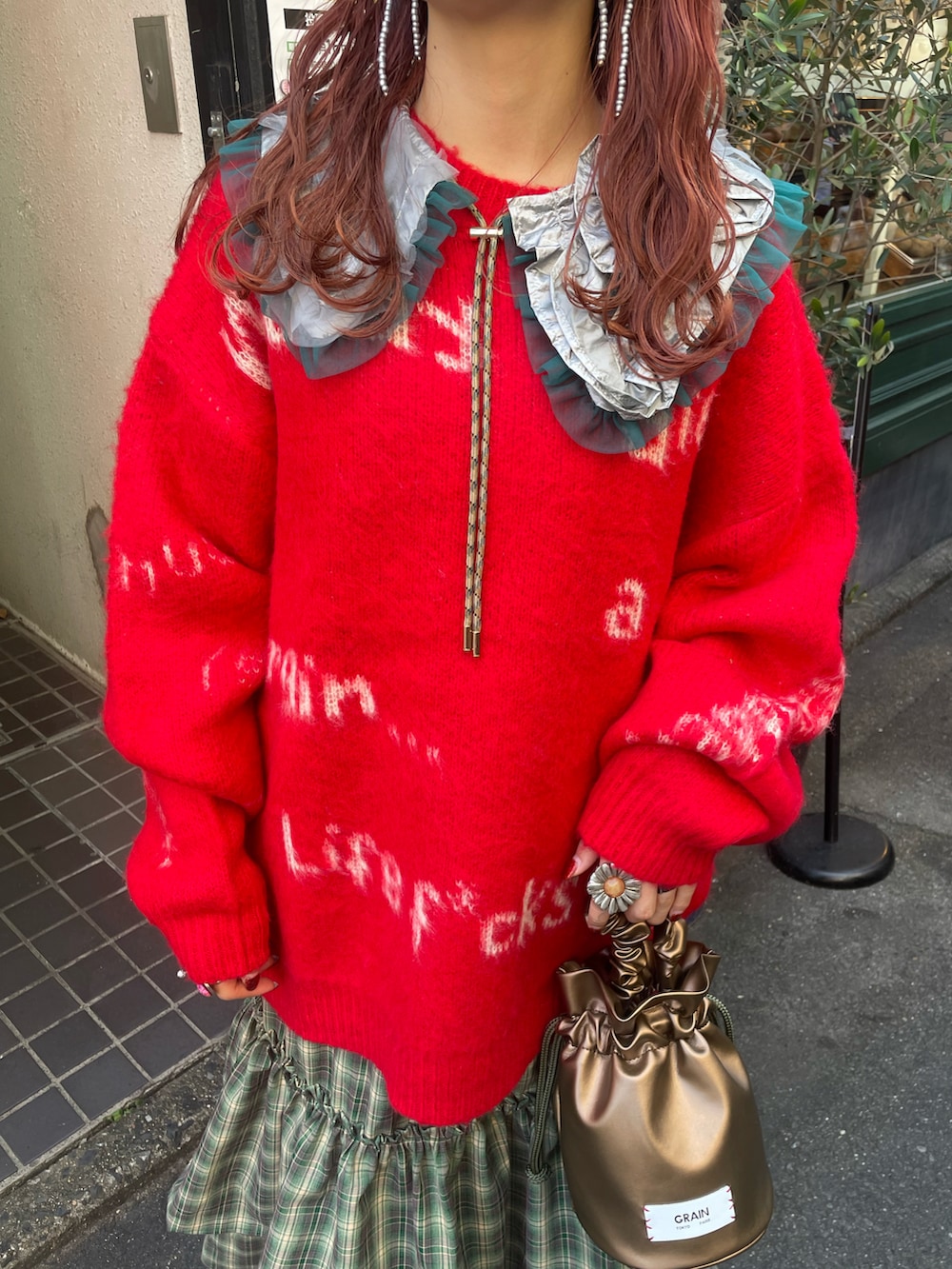 レッド系のニット/セーター、グリーン系のワンピース、ゴールド系のハンドバッグを着用したレディースの秋コーディネートの4枚目の写真