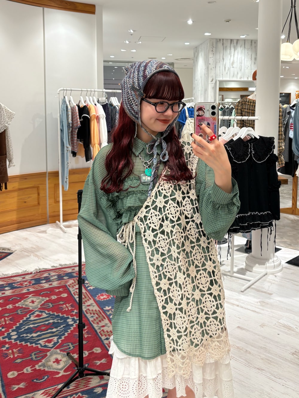 グリーン系のシャツ/ブラウス、ベージュ系のベスト、ホワイト系のスカートを着用したレディースの春コーディネートの2枚目の写真