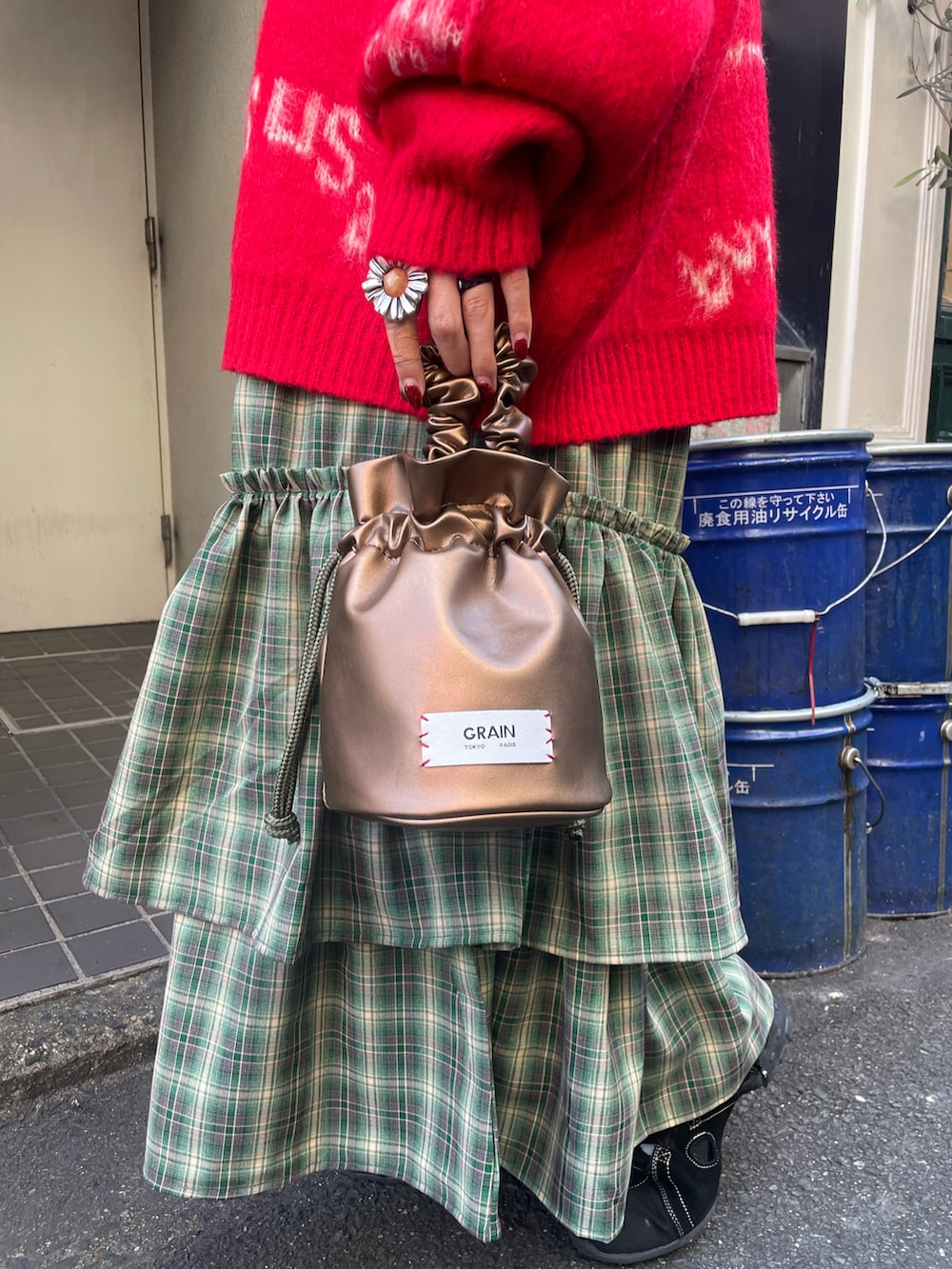 レッド系のニット/セーター、グリーン系のワンピース、ゴールド系のハンドバッグを着用したレディースの秋コーディネートの5枚目の写真