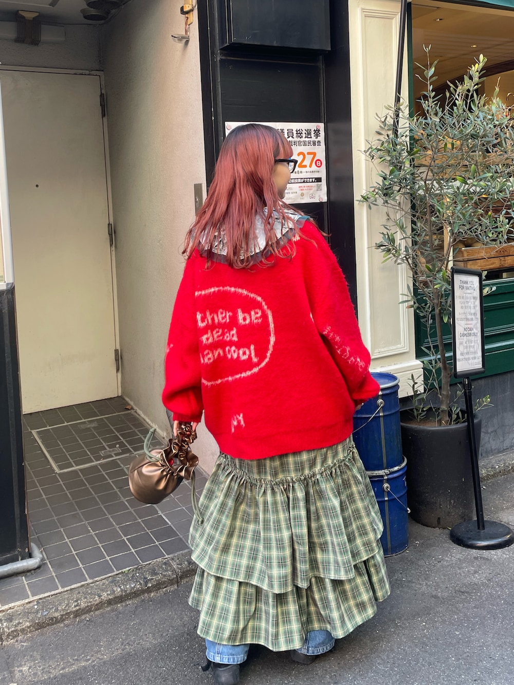 レッド系のニット/セーター、グリーン系のワンピース、ゴールド系のハンドバッグを着用したレディースの秋コーディネートの3枚目の写真