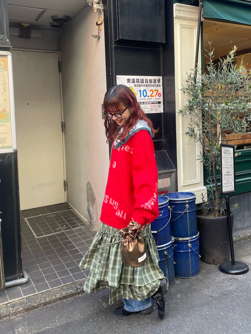 レッド系のニット/セーター、グリーン系のワンピース、ゴールド系のハンドバッグを着用したレディースの秋コーディネートの2枚目の写真