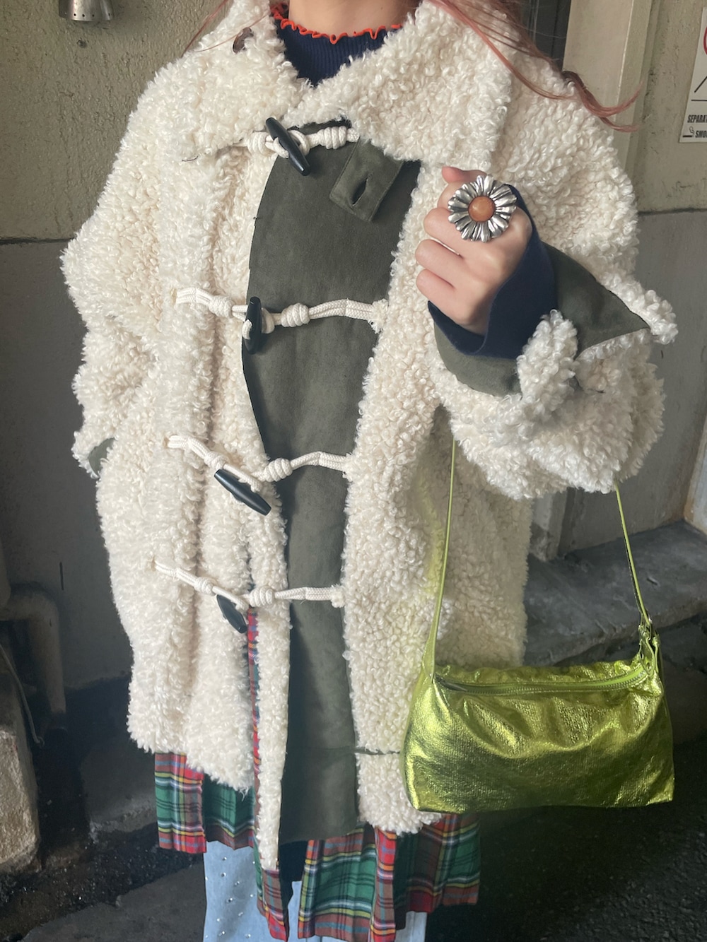 ホワイト系のダッフルコート、グリーン系のハンドバッグ、ブルー系のデニムパンツを着用したレディースの冬コーディネートの4枚目の写真