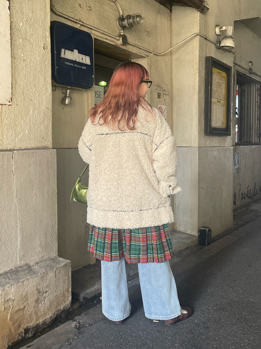 ホワイト系のダッフルコート、グリーン系のハンドバッグ、ブルー系のデニムパンツを着用したレディースの冬コーディネートの3枚目の写真