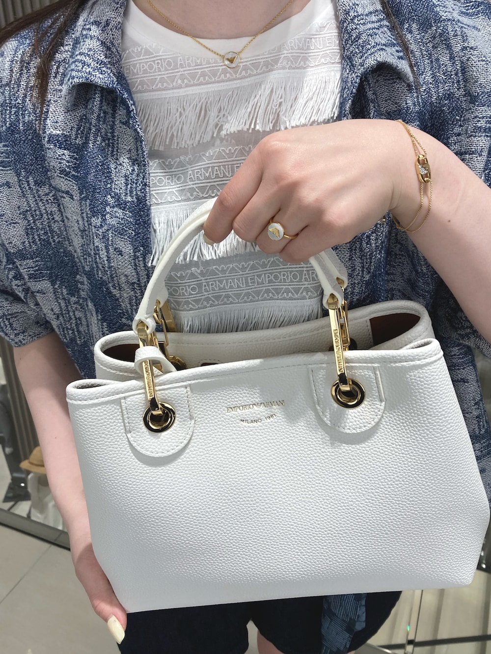 ブルー系のシャツ/ブラウス、ホワイト系のTシャツ/カットソー、ホワイト系のハンドバッグを着用したレディースの春コーディネートの2枚目の写真