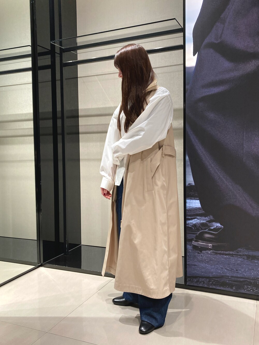 ベージュ系のトレンチコート、ブルー系のデニムパンツ、ブラック系のショルダーバッグを着用したレディースの冬コーディネートの4枚目の写真