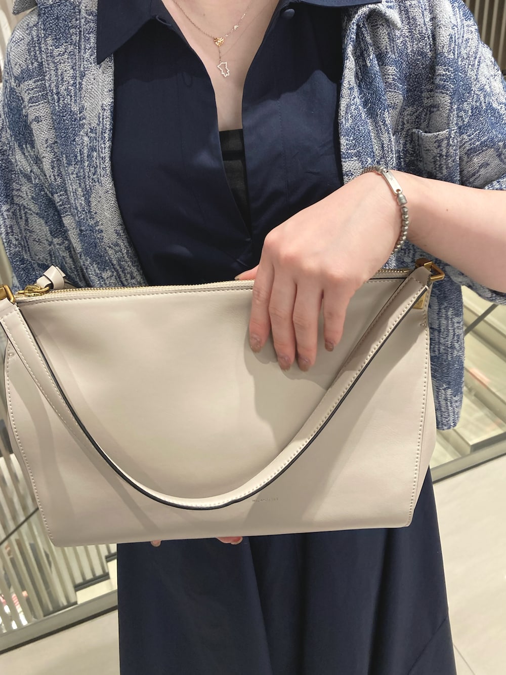 ブルー系のシャツ/ブラウス、ブルー系のワンピース、ベージュ系のハンドバッグを着用したレディースの春コーディネートの2枚目の写真