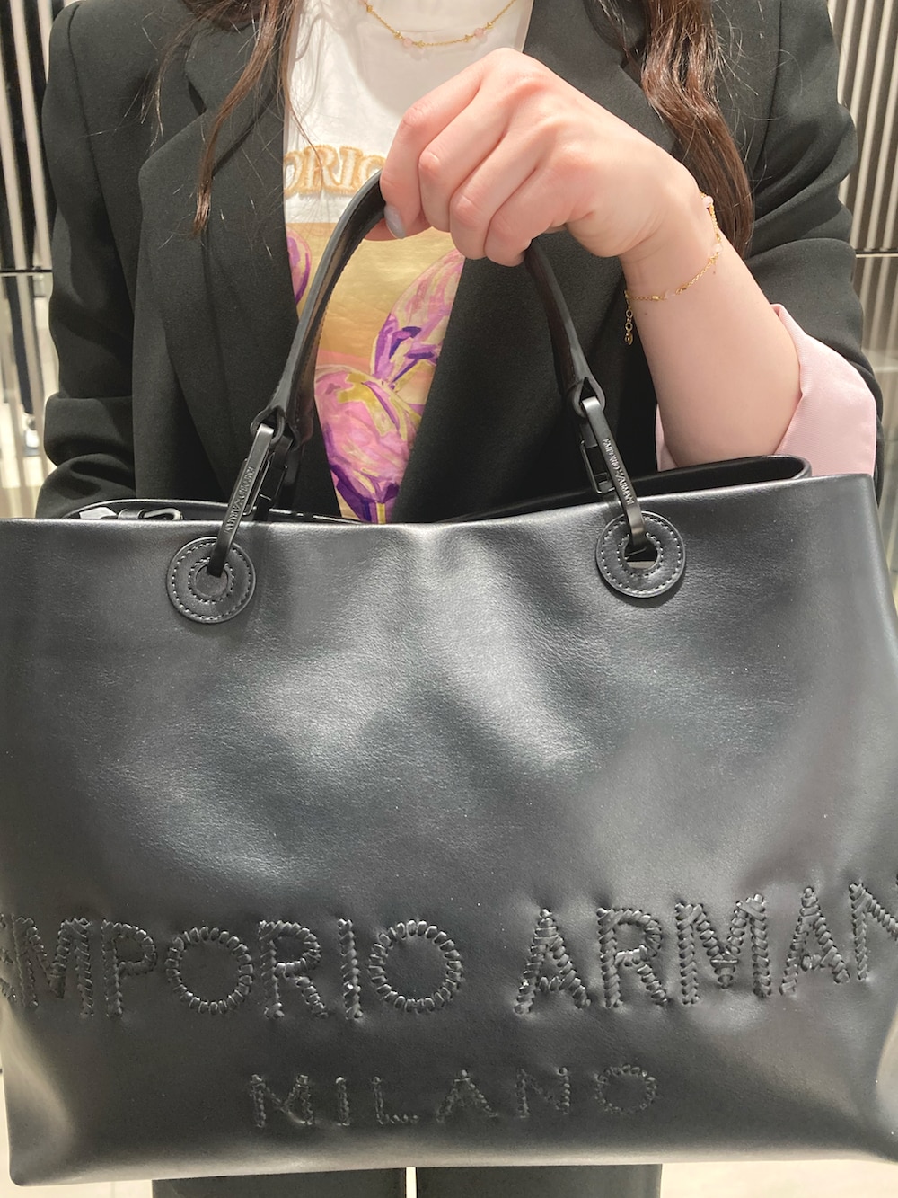 ホワイト系のTシャツ/カットソー、ブラック系のトートバッグ、ゴールド系のブレスレットを着用したレディースの春コーディネートの2枚目の写真