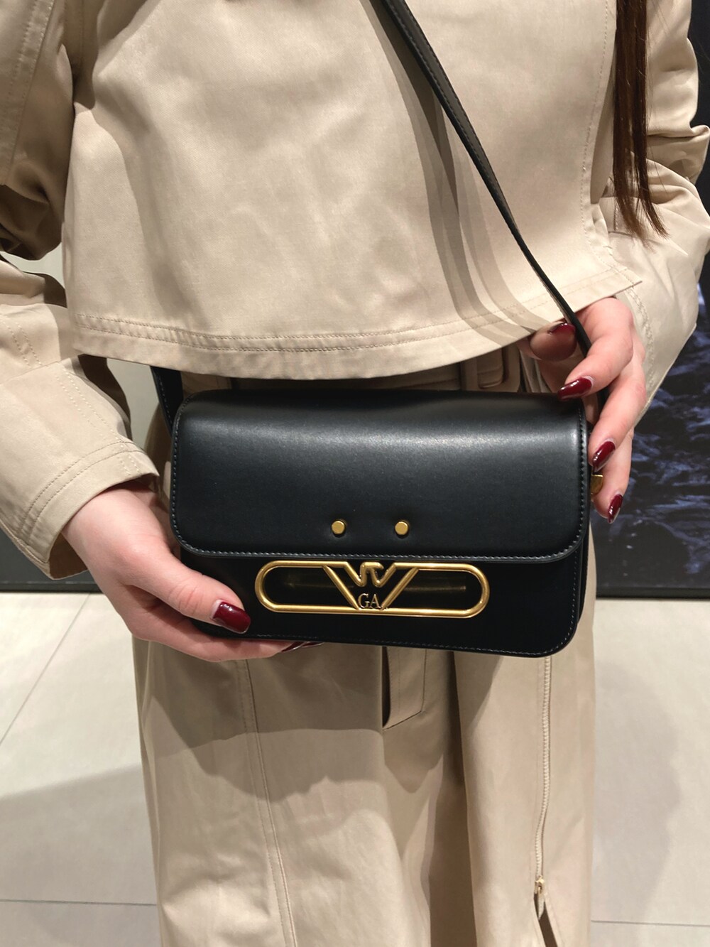 ベージュ系のトレンチコート、ブルー系のデニムパンツ、ブラック系のショルダーバッグを着用したレディースの冬コーディネートの5枚目の写真