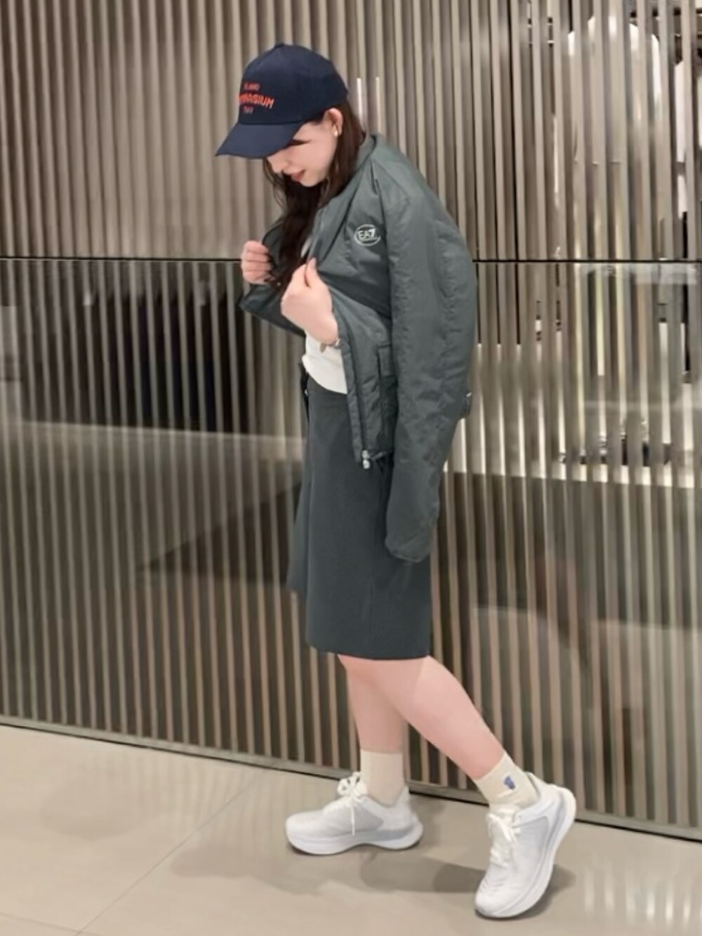 グリーン系のパンツ、ブラック系のショルダーバッグ、ホワイト系のスニーカーを着用したレディースの春コーディネートの2枚目の写真