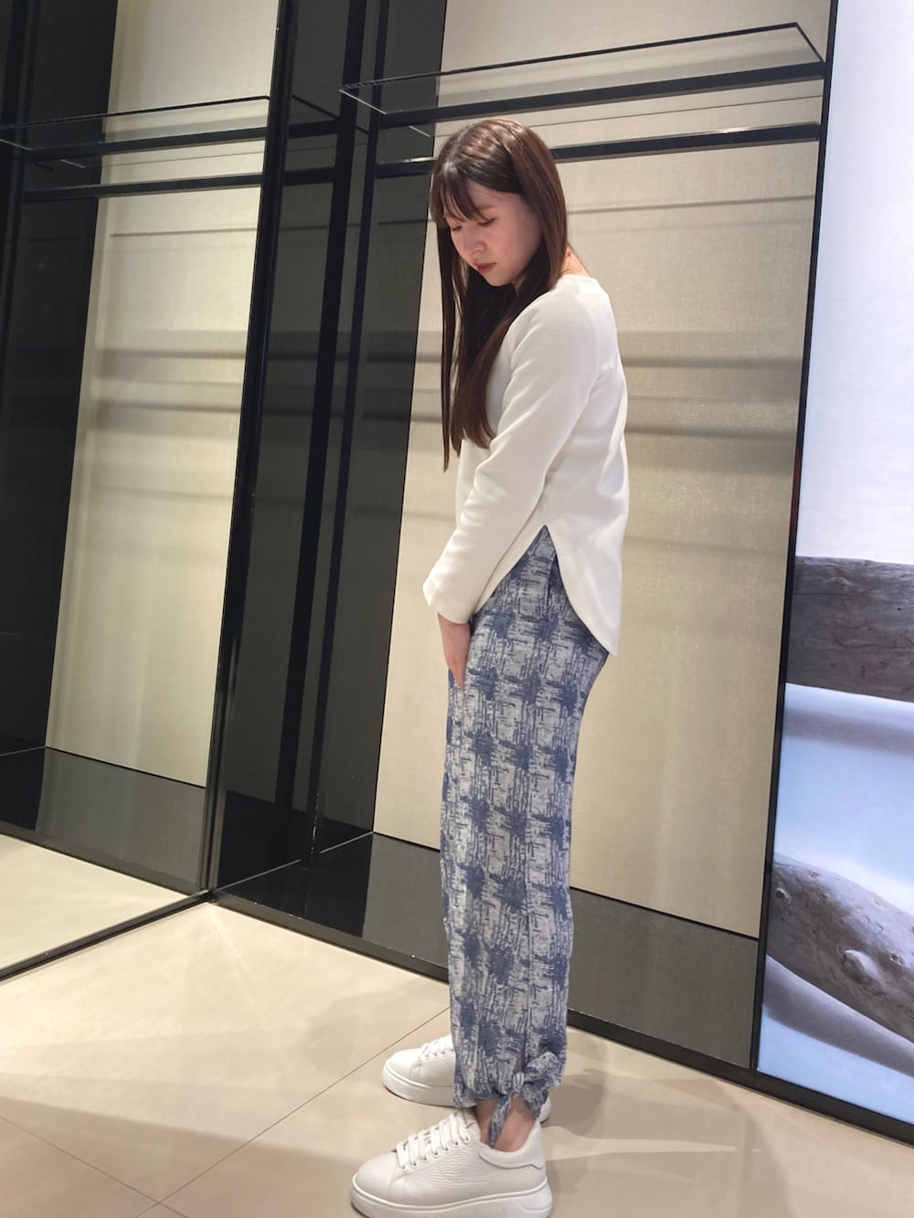 ブルー系のショルダーバッグ、ホワイト系のニット/セーター、ブルー系のその他パンツを着用したレディースの冬コーディネートの2枚目の写真