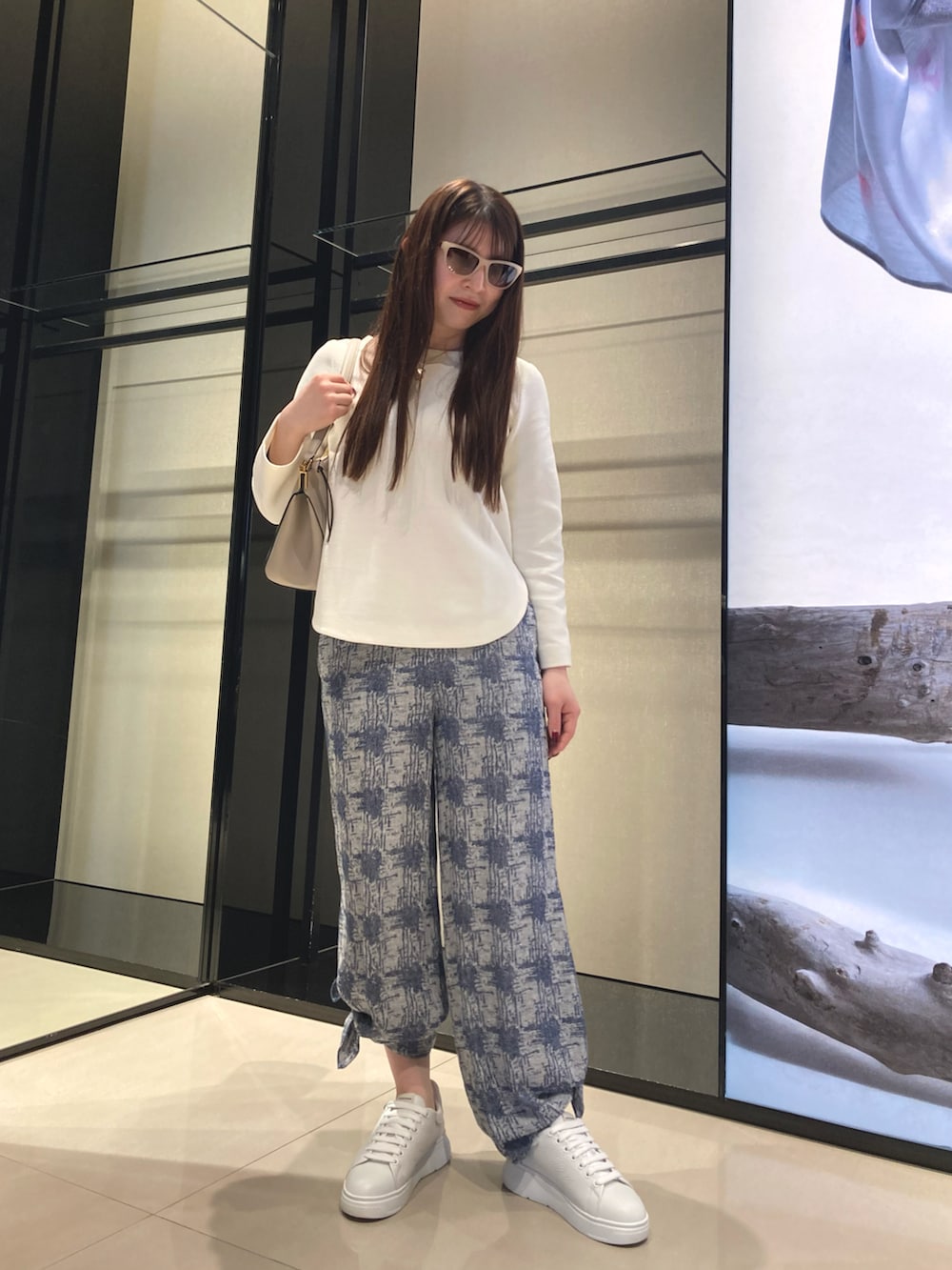 ブルー系のショルダーバッグ、ホワイト系のニット/セーター、ブルー系のその他パンツを着用したレディースの冬コーディネートの3枚目の写真