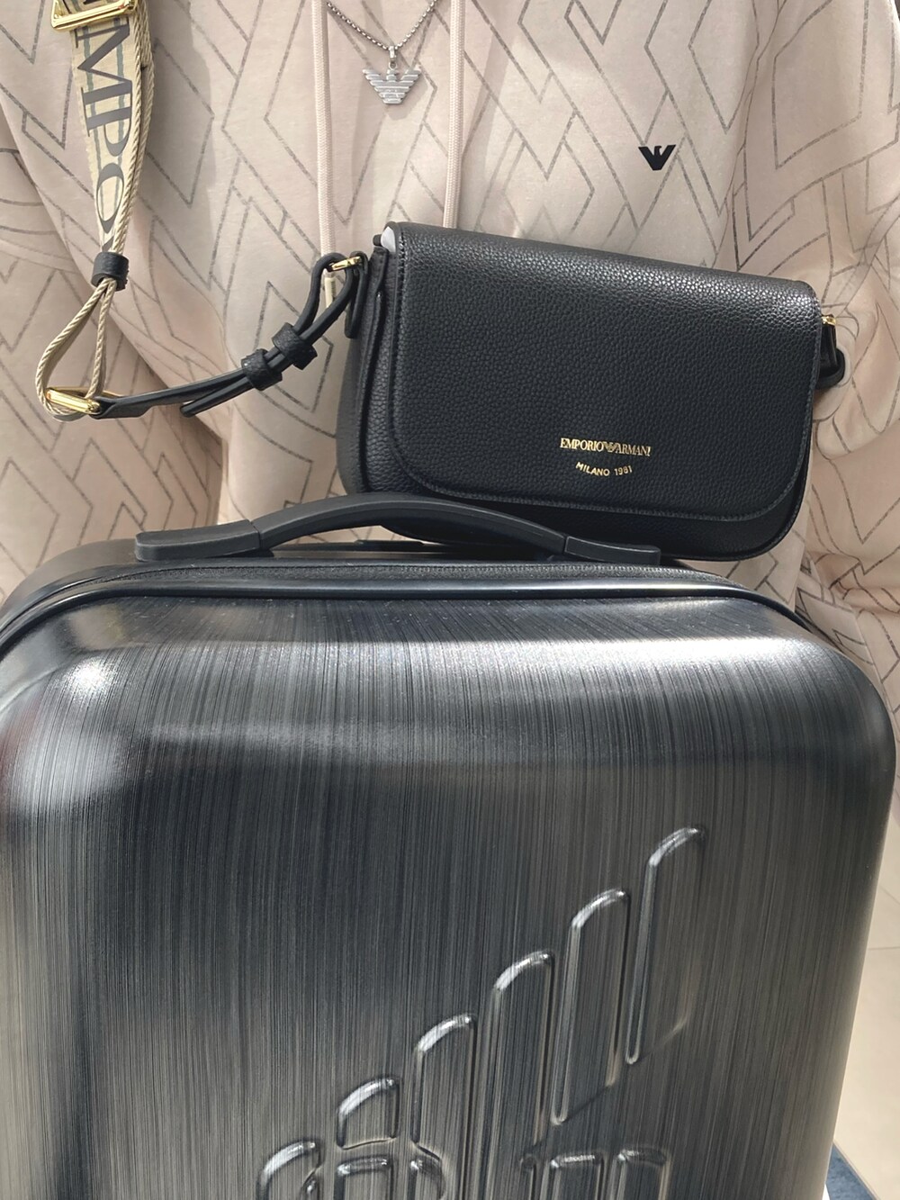 ブルー系のスウェット、ブラック系のショルダーバッグ、グレー系のスーツケース/キャリーバッグを着用したレディースの夏コーディネートの2枚目の写真