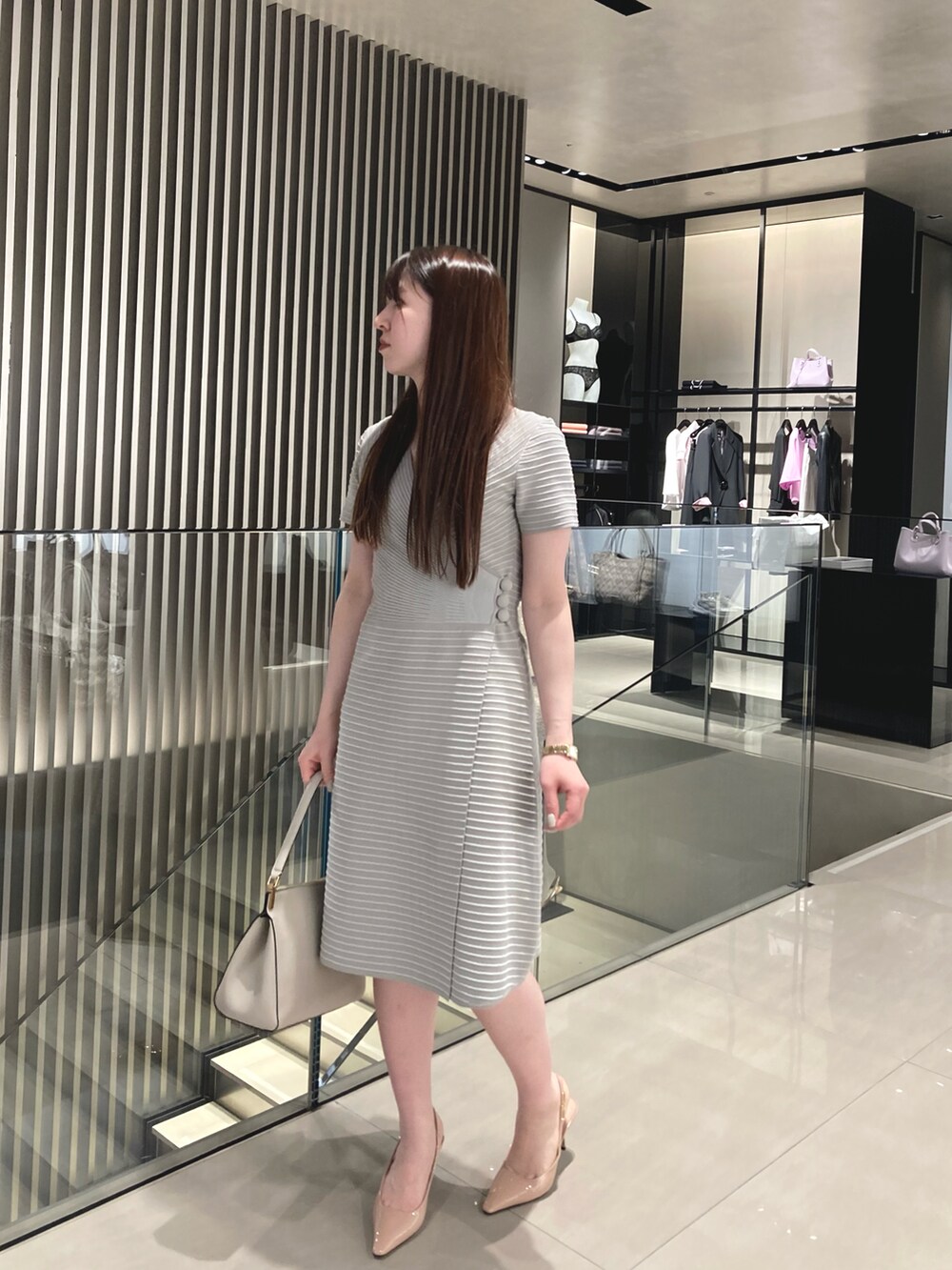 グレー系のドレス、ベージュ系のパンプス、ベージュ系のハンドバッグを着用したレディースの冬コーディネートの2枚目の写真