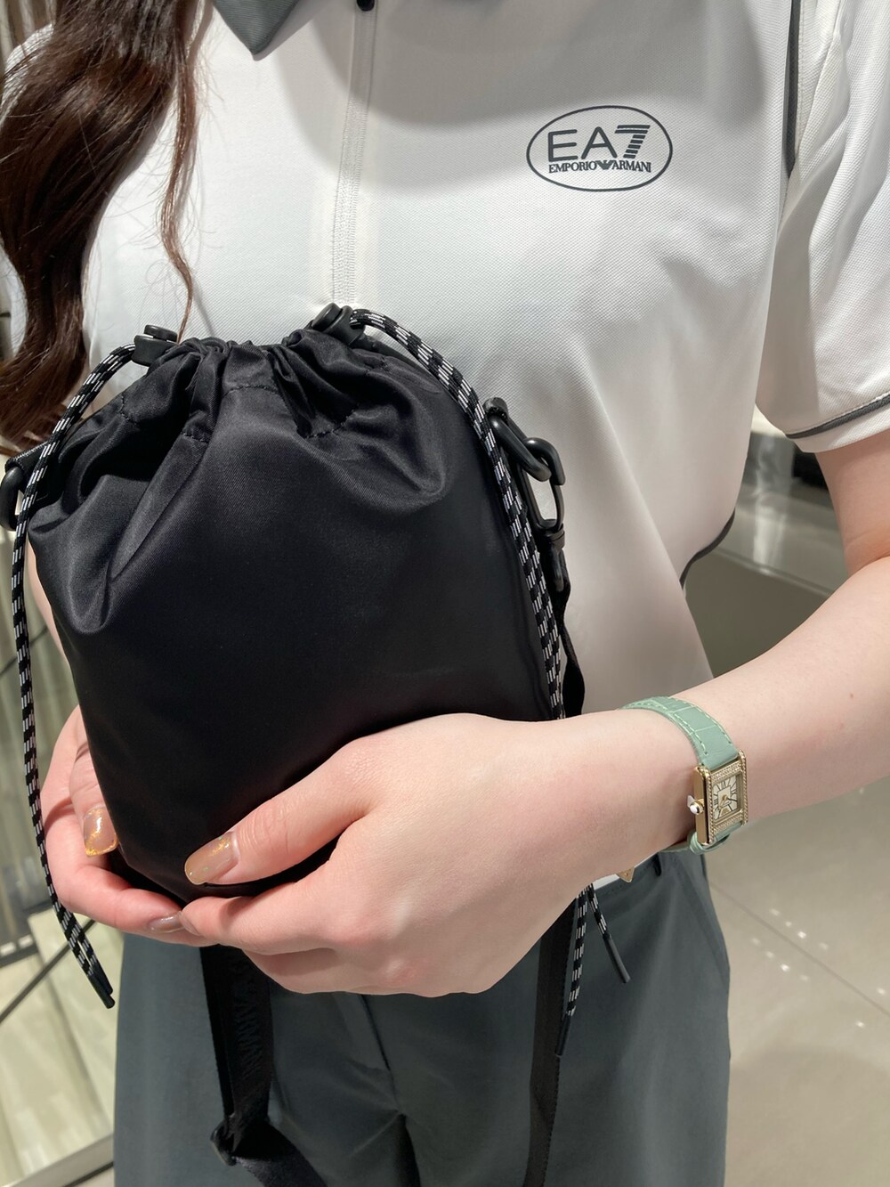 グリーン系のパンツ、ブラック系のショルダーバッグ、ホワイト系のスニーカーを着用したレディースの春コーディネートの3枚目の写真