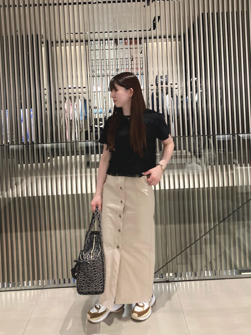 ブルー系のトートバッグ、ホワイト系のTシャツ/カットソー、ベージュ系のスカートを着用したレディースの冬コーディネートの2枚目の写真