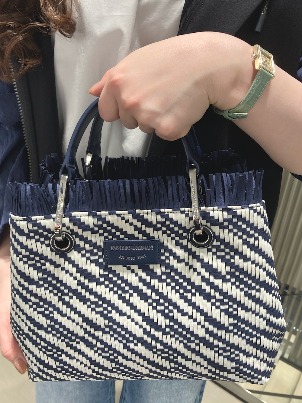 ブラック系のブルゾン、ホワイト系のシャツ/ブラウス、ブルー系のトートバッグを着用したレディースの春コーディネートの2枚目の写真