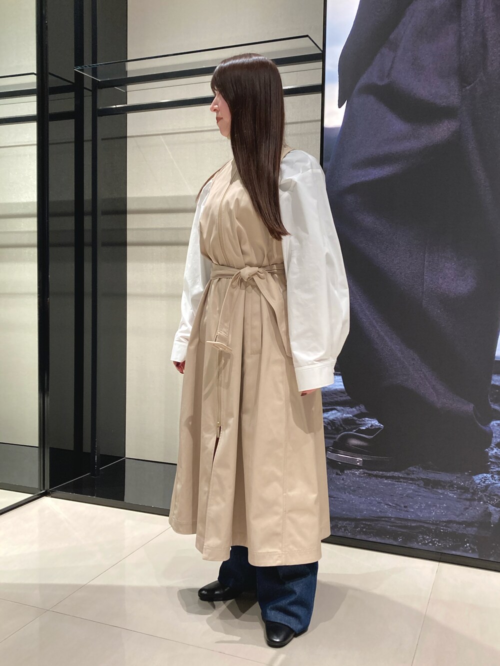 ベージュ系のトレンチコート、ブルー系のデニムパンツ、ブラック系のショルダーバッグを着用したレディースの冬コーディネートの3枚目の写真