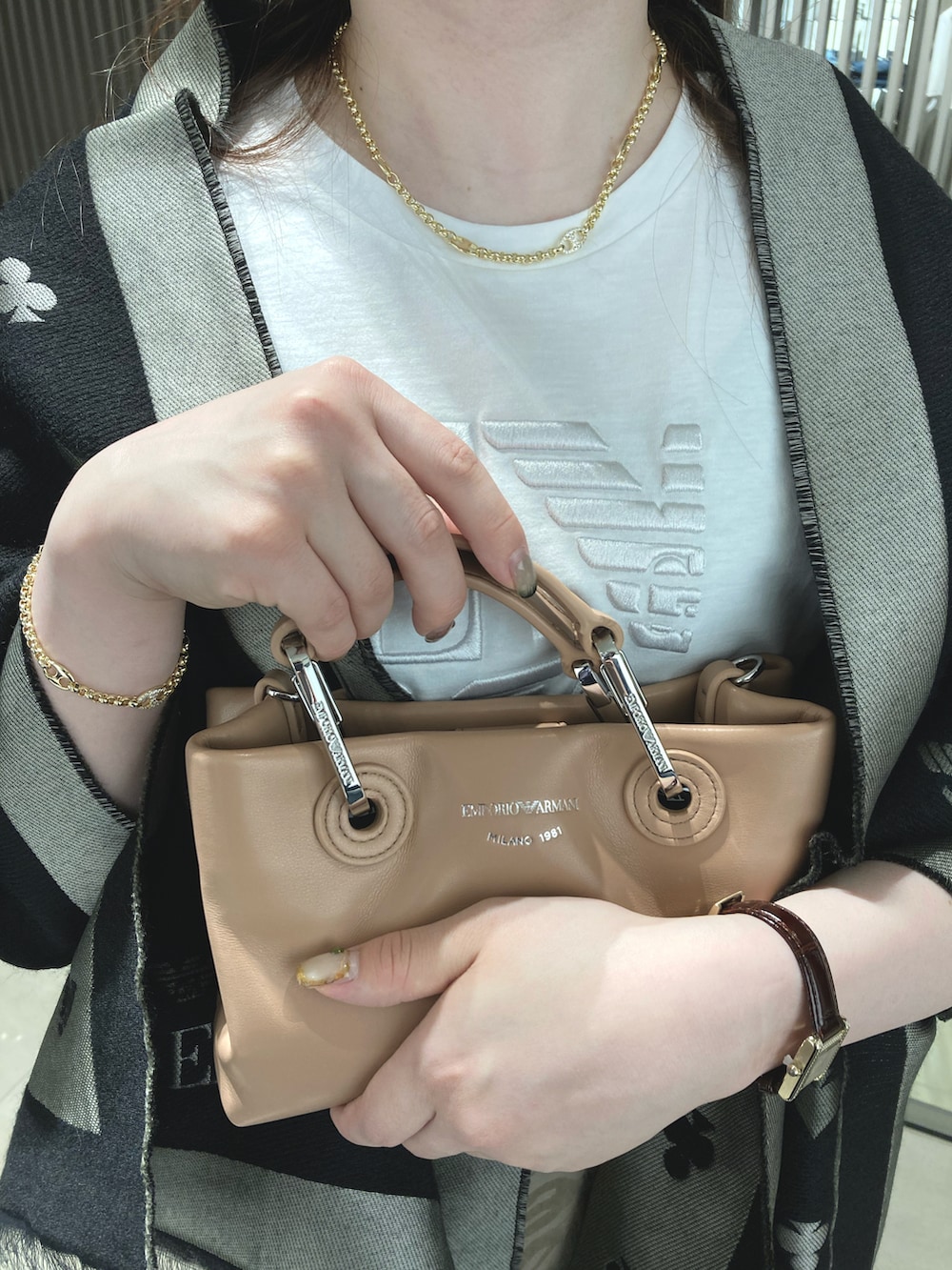 ホワイト系のTシャツ/カットソー、ブラック系のハンドバッグ、ブラック系のストール/ショールを着用したレディースの秋コーディネートの2枚目の写真