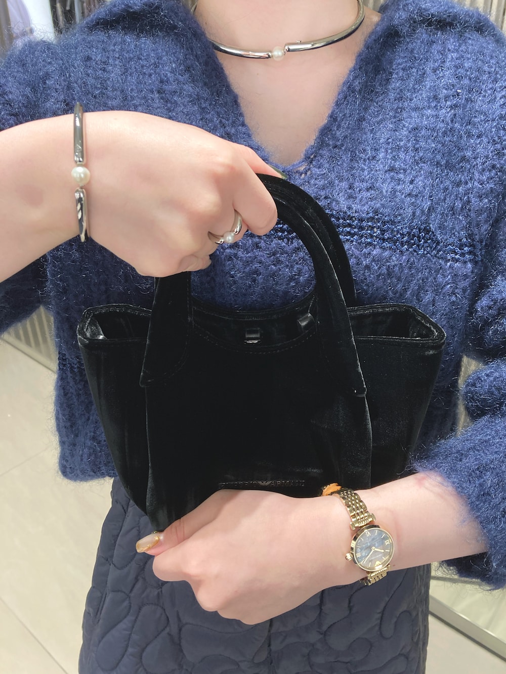 ブルー系のスカート、ブラック系のハンドバッグ、シルバー系のピアス(両耳用)を着用したレディースの秋コーディネートの2枚目の写真