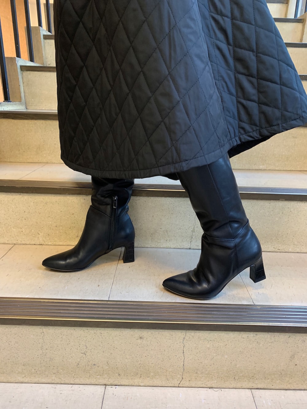 ブラック系のスカート、ブラック系のブーツを着用したレディースの冬コーディネートの2枚目の写真