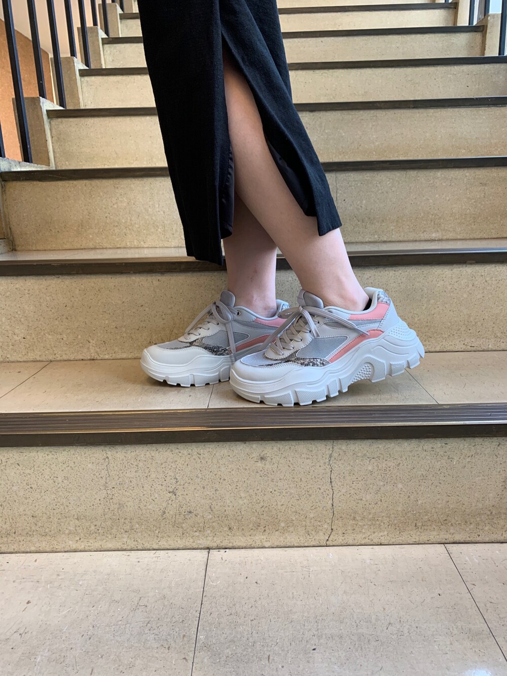 グレー系のスニーカー、ホワイト系のマウンテンパーカー、ブラック系のスカートを着用したレディースの秋コーディネートの2枚目の写真