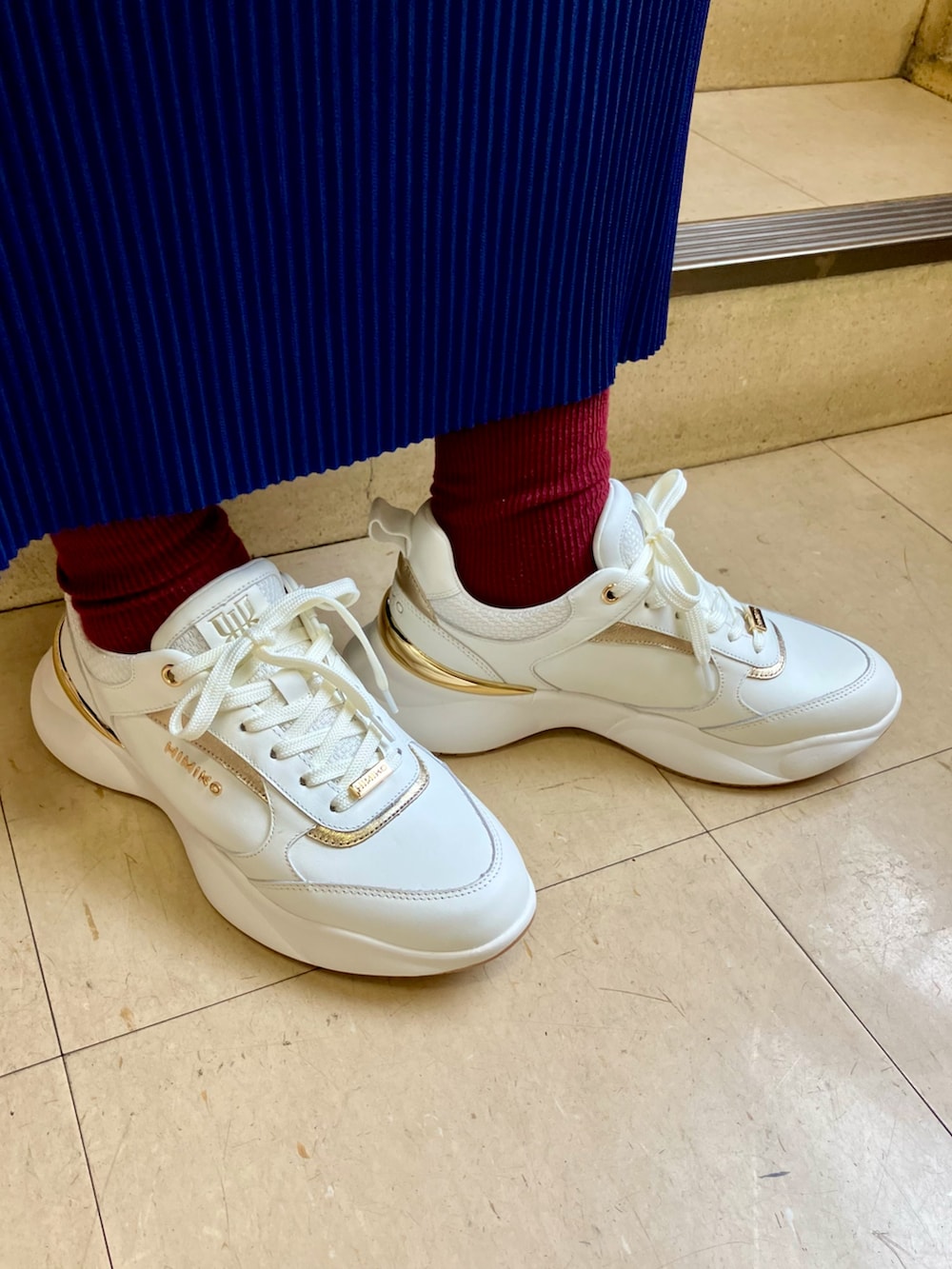 ホワイト系のスニーカーを着用したレディースの秋コーディネートの2枚目の写真