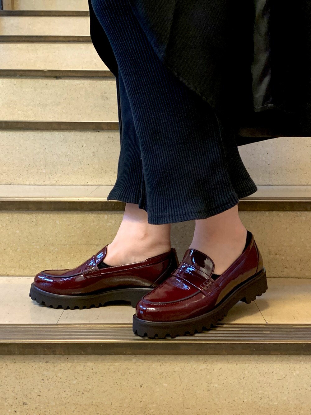 ブラック系のジャンパースカート、レッド系のローファーを着用したレディースの冬コーディネートの2枚目の写真