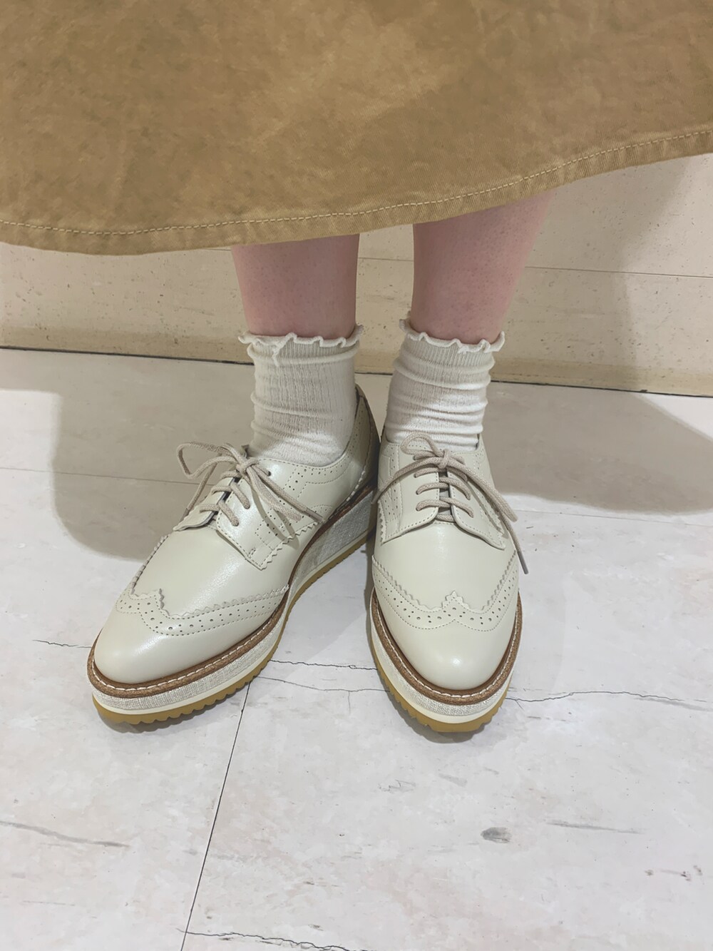 ホワイト系のパンプスを着用したレディースの春コーディネートの2枚目の写真