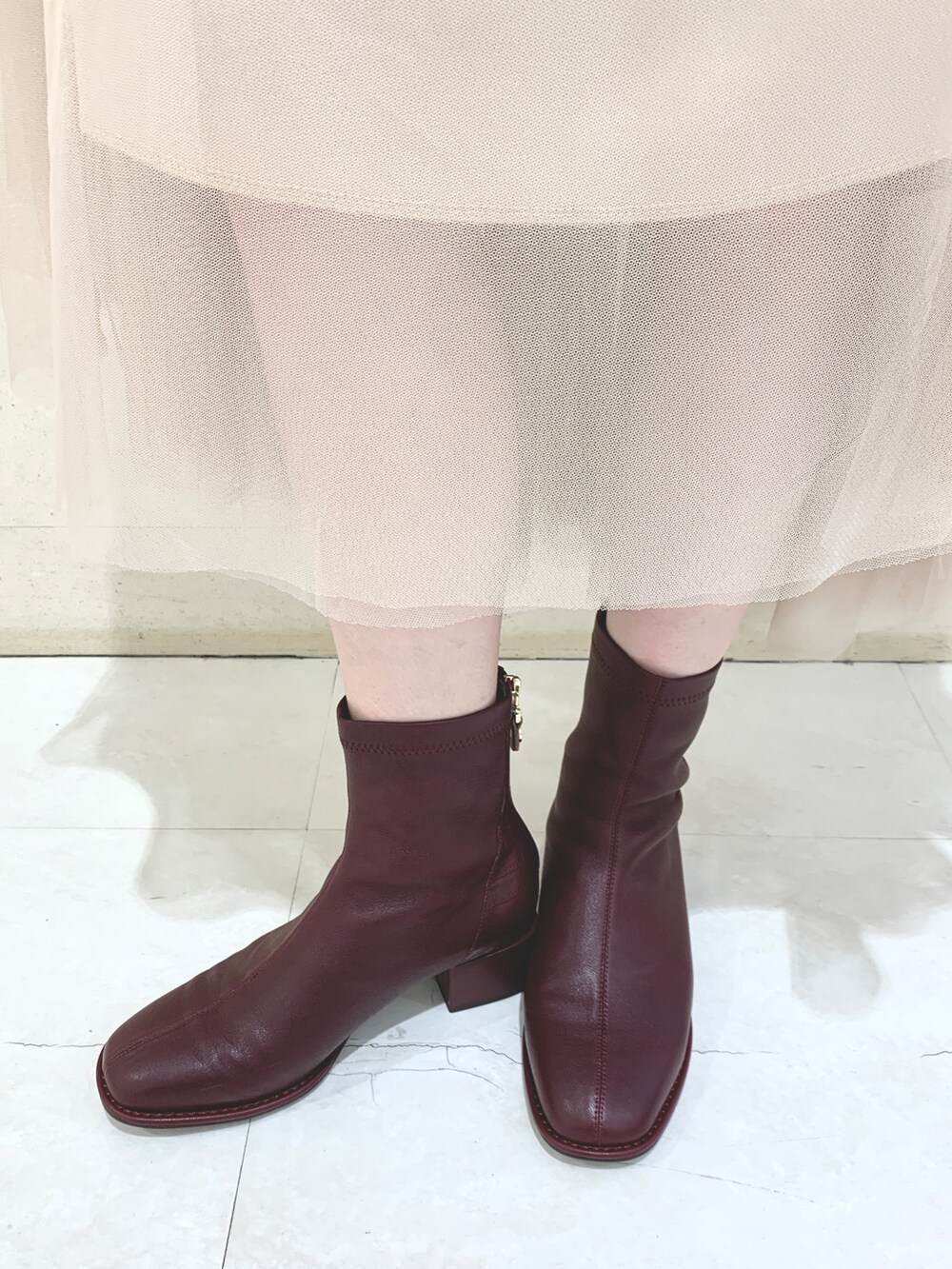 レッド系のブーツを着用したレディースの秋コーディネートの2枚目の写真